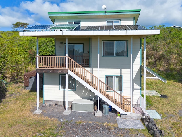 rear view of property with metal roof, a yard, and stairway