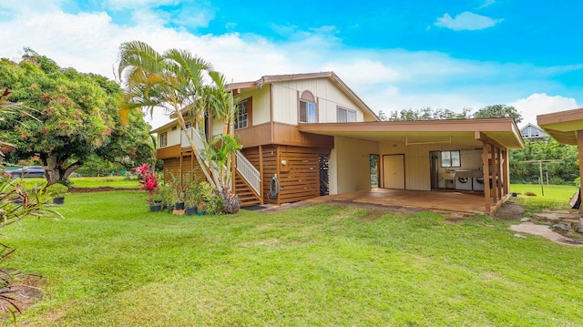 rear view of property with a carport, a lawn, driveway, and stairs