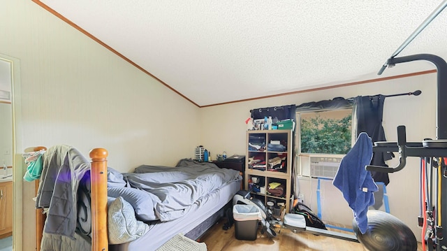 bedroom featuring lofted ceiling, ornamental molding, a textured ceiling, and wood finished floors