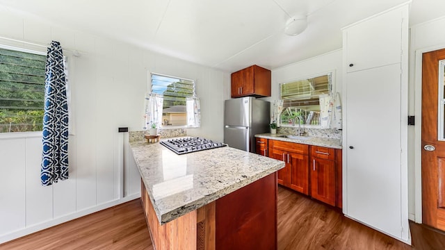 kitchen featuring light stone counters, dark wood finished floors, a sink, and freestanding refrigerator