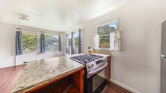 kitchen featuring dark wood-type flooring, baseboards, stainless steel range with gas stovetop, and light stone counters