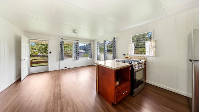 kitchen featuring appliances with stainless steel finishes, plenty of natural light, light stone counters, and dark wood-style floors