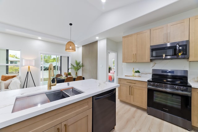 kitchen with pendant lighting, lofted ceiling, light brown cabinetry, appliances with stainless steel finishes, and a sink