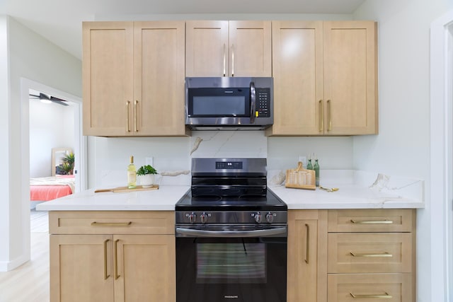 kitchen featuring light stone countertops, appliances with stainless steel finishes, light wood-style floors, and light brown cabinetry