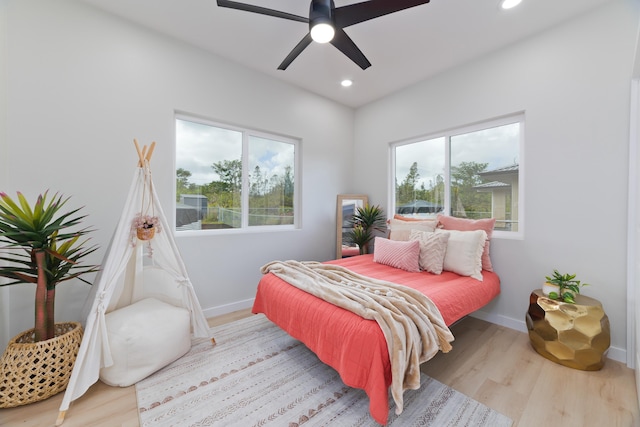 bedroom with light wood-style floors, multiple windows, and baseboards