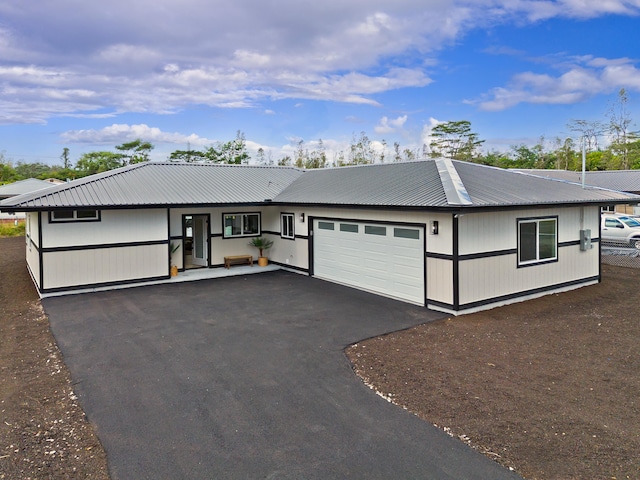 view of front facade featuring a garage, metal roof, and driveway