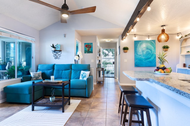 living room with lofted ceiling, light tile patterned floors, a ceiling fan, and baseboards