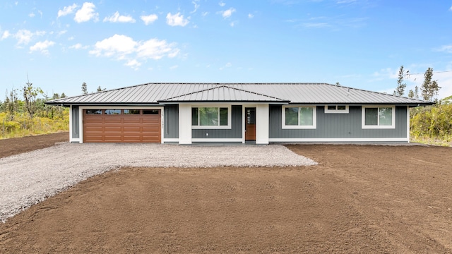 single story home featuring a garage, metal roof, and gravel driveway