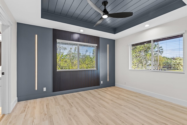 unfurnished room with a tray ceiling, wooden ceiling, light wood-style flooring, and baseboards