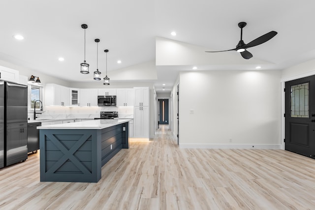 kitchen featuring white cabinets, light countertops, a center island, black appliances, and glass insert cabinets