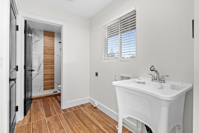 full bathroom featuring a stall shower, baseboards, toilet, wood finished floors, and a sink