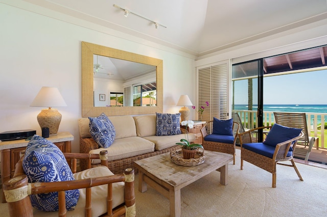 living room with crown molding, lofted ceiling, light colored carpet, a water view, and track lighting