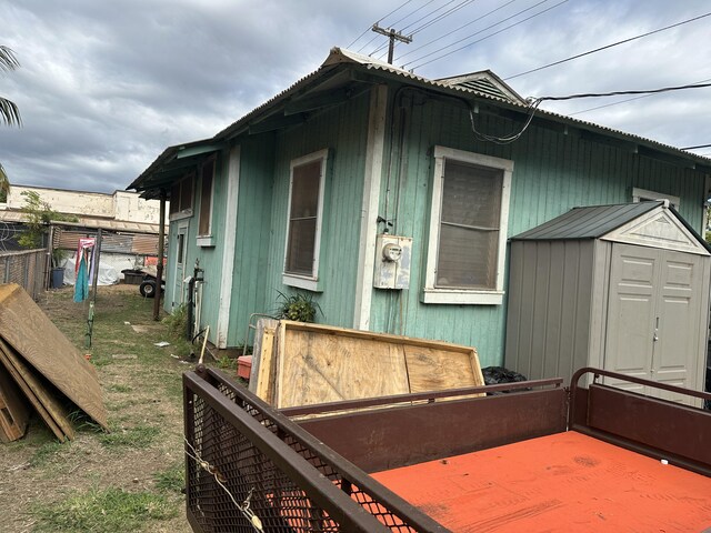 view of side of property with fence, an outdoor structure, and a storage unit