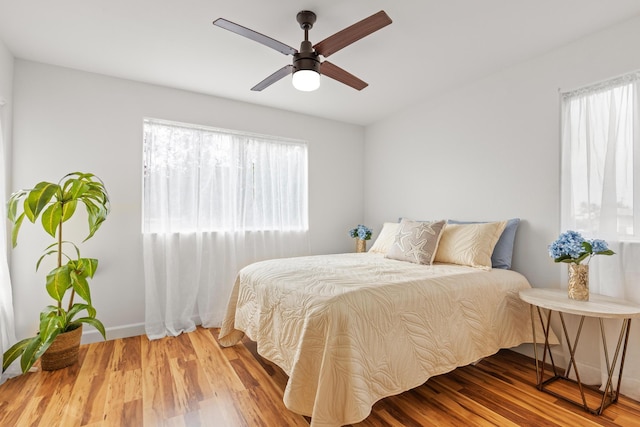 bedroom with a ceiling fan, baseboards, and wood finished floors