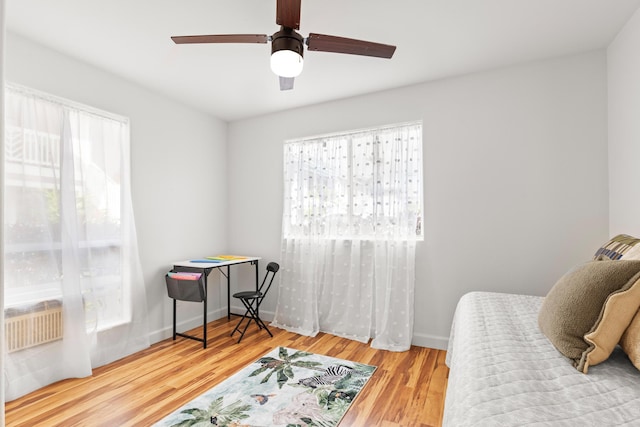 bedroom featuring multiple windows, ceiling fan, baseboards, and wood finished floors