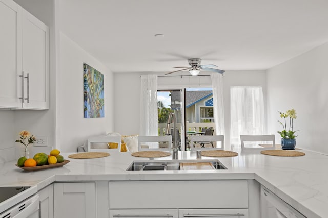 kitchen featuring white cabinets, a sink, white dishwasher, and stove