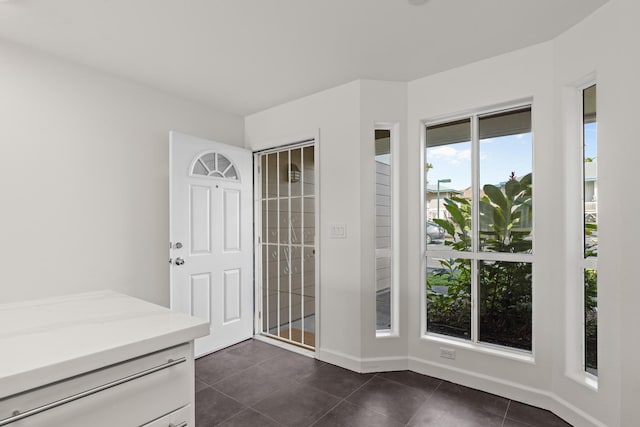 doorway featuring dark tile patterned floors and baseboards