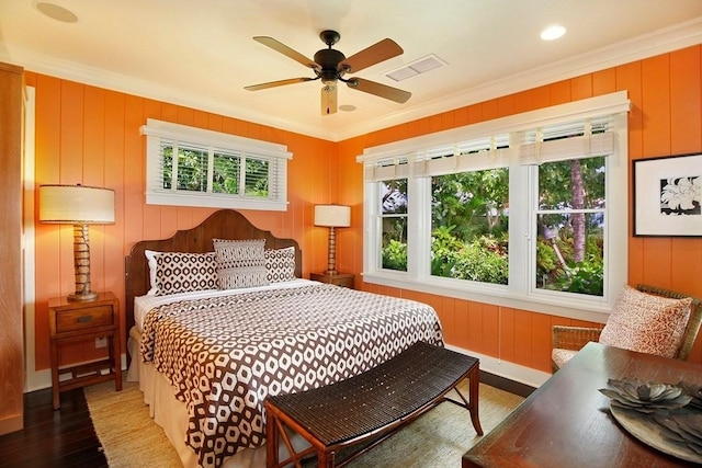 bedroom with wood finished floors, a ceiling fan, baseboards, visible vents, and crown molding