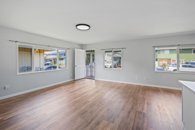 spare room with plenty of natural light, baseboards, and wood finished floors