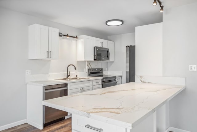 kitchen with appliances with stainless steel finishes, white cabinetry, a sink, and a peninsula