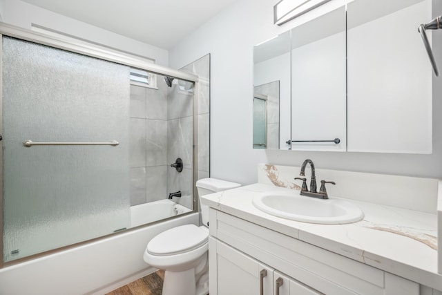 full bath with wood finished floors, vanity, toilet, and bath / shower combo with glass door