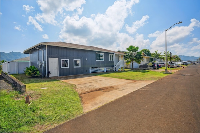 view of front of house featuring fence, a mountain view, and a front lawn