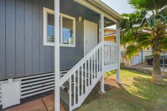 view of exterior entry with a yard and fence