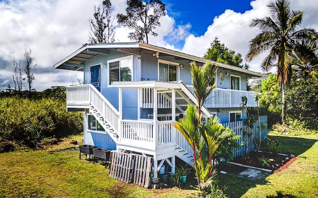 back of property featuring stairway and a lawn