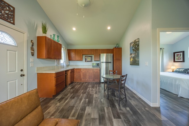 kitchen with high vaulted ceiling, stainless steel appliances, dark wood-type flooring, a sink, and light countertops