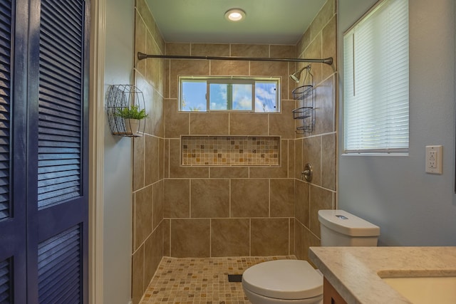 full bathroom featuring tiled shower, vanity, and toilet