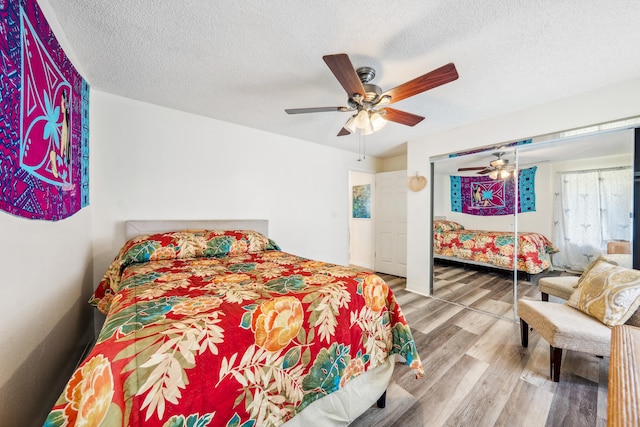 bedroom with a textured ceiling, wood finished floors, and a ceiling fan