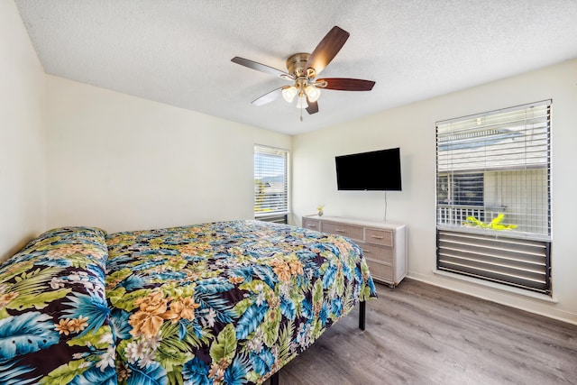 bedroom with a ceiling fan, a textured ceiling, and wood finished floors