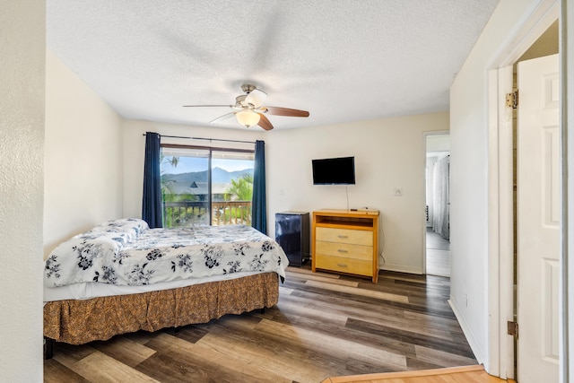 bedroom with a textured ceiling, ceiling fan, dark wood-style flooring, and baseboards