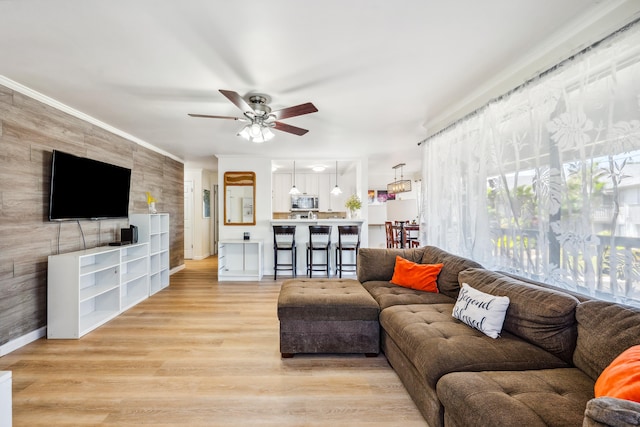 living room featuring light wood-style floors, crown molding, and ceiling fan