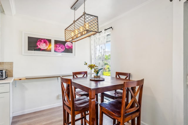 dining space with light wood-type flooring, crown molding, and baseboards