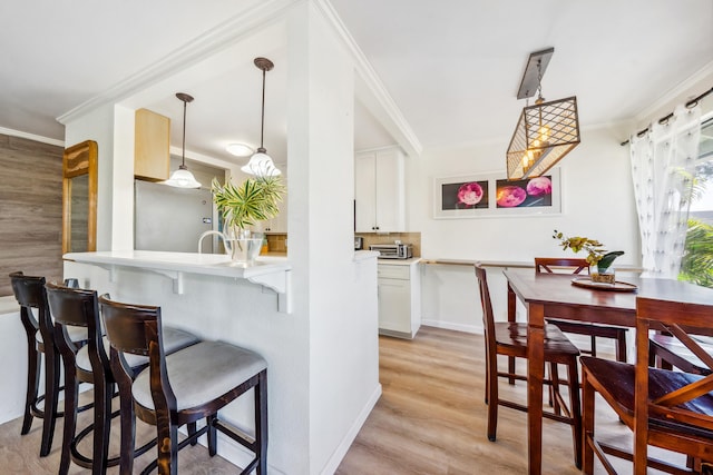 kitchen with light countertops, decorative light fixtures, a kitchen bar, and white cabinetry