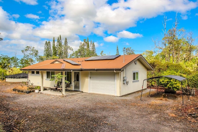 view of front of property with a garage, stucco siding, dirt driveway, and solar panels