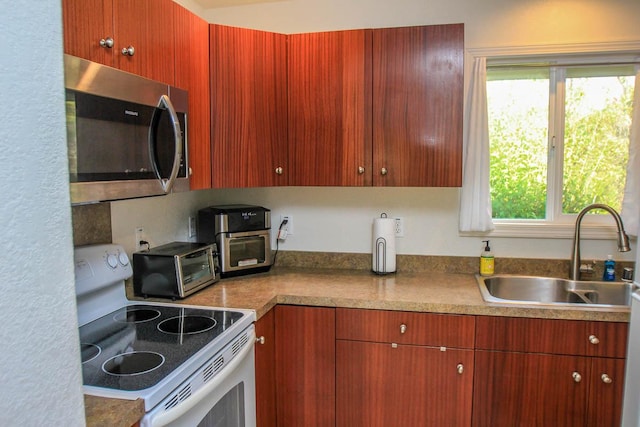 kitchen with a toaster, electric range, a sink, light countertops, and stainless steel microwave