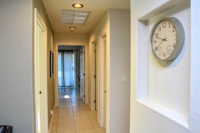 corridor with light tile patterned floors and a textured wall