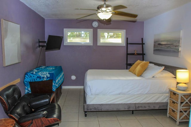 tiled bedroom featuring ceiling fan, a textured ceiling, and baseboards