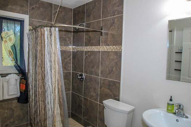 bathroom featuring a stall shower, a sink, and toilet