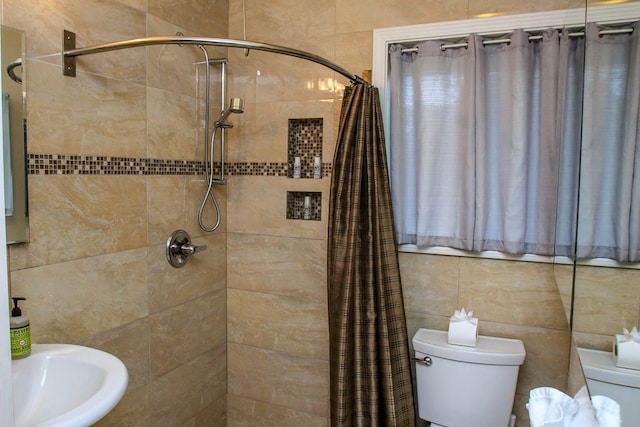 full bath with tiled shower, a sink, and toilet