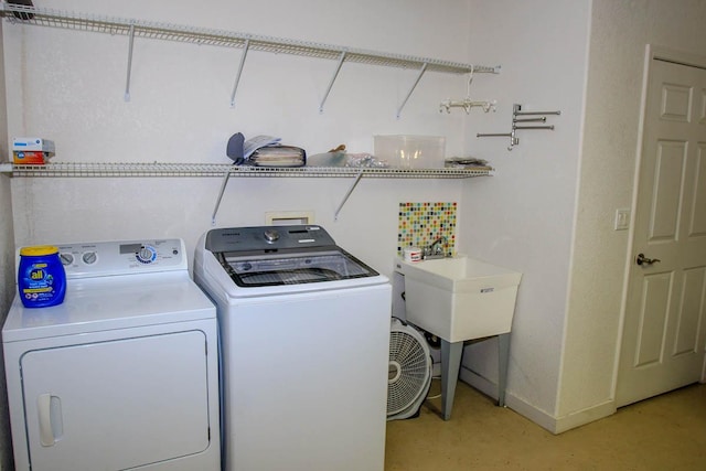 washroom featuring laundry area, washer and clothes dryer, a sink, and baseboards