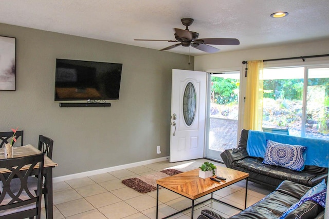 living room with light tile patterned floors, ceiling fan, baseboards, and a textured ceiling