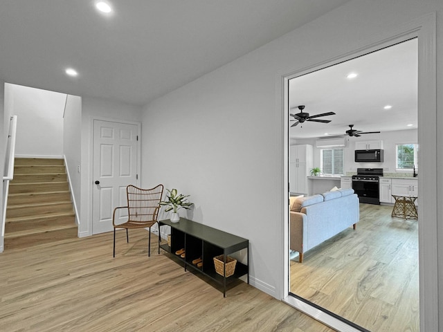 living area with recessed lighting, light wood-style flooring, and stairs