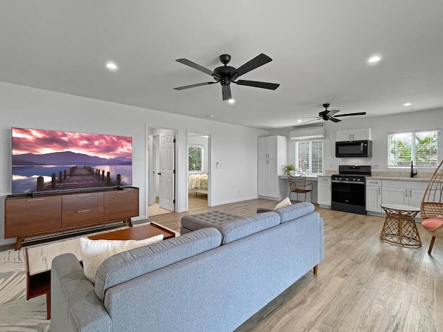 living area featuring recessed lighting, a ceiling fan, baseboards, light wood-style floors, and a wall mounted air conditioner