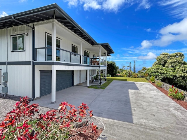 view of home's exterior with a garage, board and batten siding, and a balcony