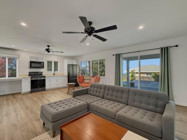 living area featuring light wood-type flooring, baseboards, a ceiling fan, and recessed lighting