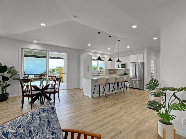 interior space featuring stainless steel appliances, a kitchen island, white cabinets, decorative backsplash, and a kitchen bar