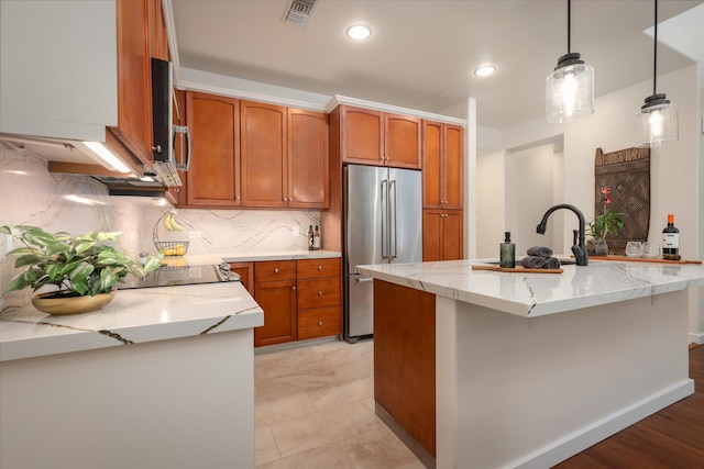 kitchen featuring high quality fridge, visible vents, brown cabinetry, and decorative light fixtures